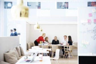 A team of five are having a meeting around a large table in a group space offered by OP Vallila