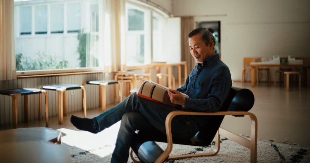 Man sitting in a chair reading a book.