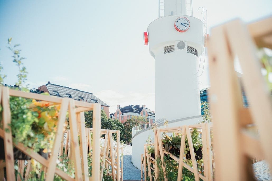 View looking up at the Lasipalatsi tower from between the tall, wooden frame planters of Keidas, an Oasis plant installation and meeting place filled with lush greenery.