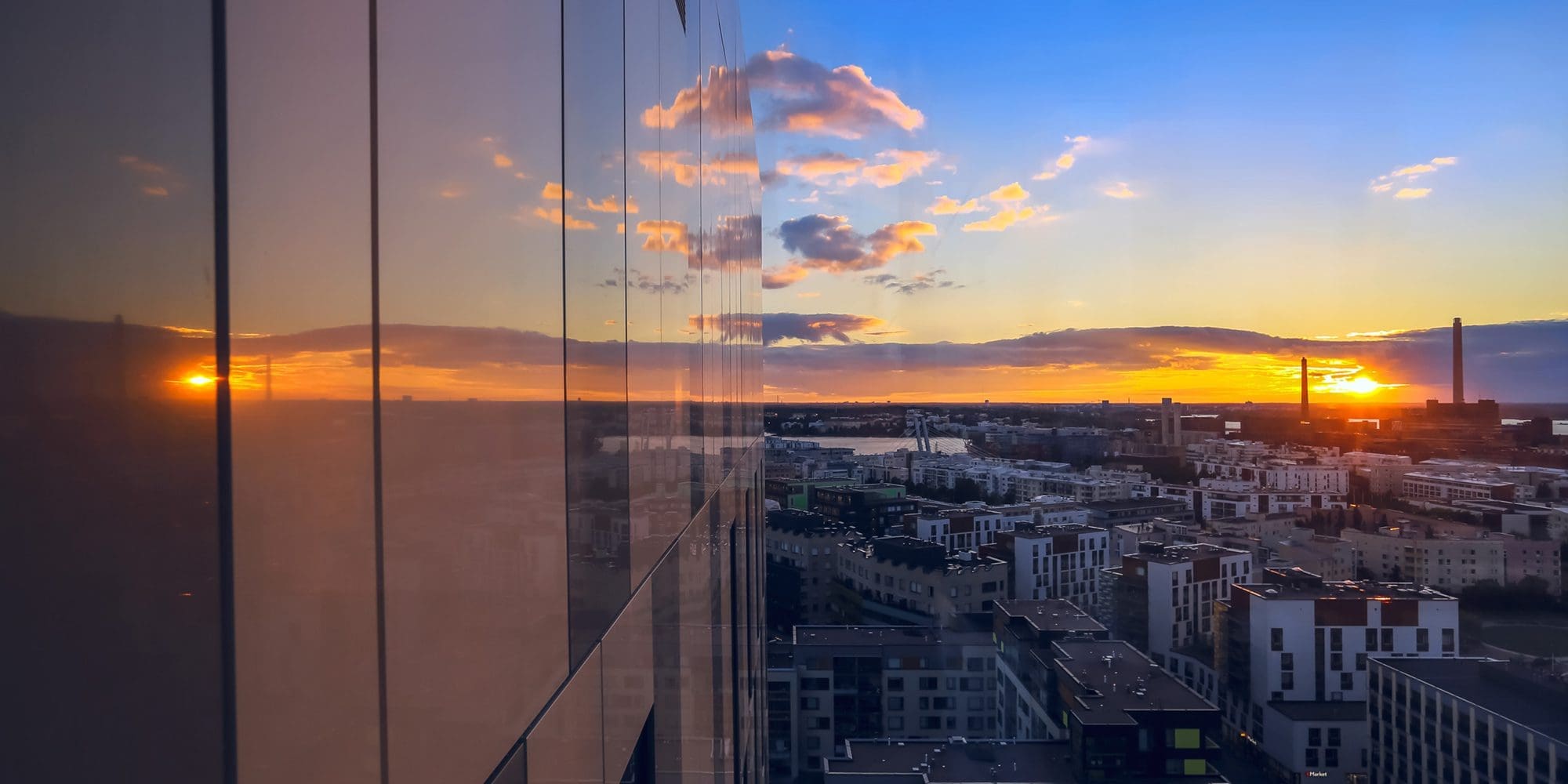 View from Clarion Helsinki to Jätkäsaari area. In this shot part of the Clarion's glass building is visible as well as the aerial view of Jätkäsaari during the sunset in the summer.