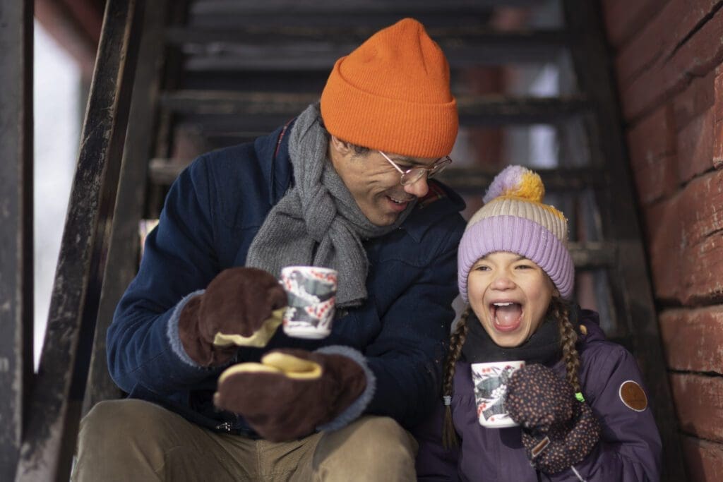 A man and child drinking a warm cup on the stair in the winter