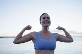 Woman in a swimsuit arms up representing strength in front of a frozen lake