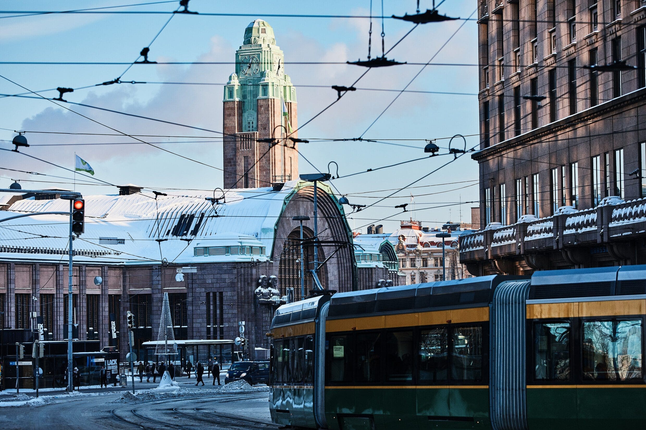Tram turning a corner in front of Helsinki Central Station in the winter