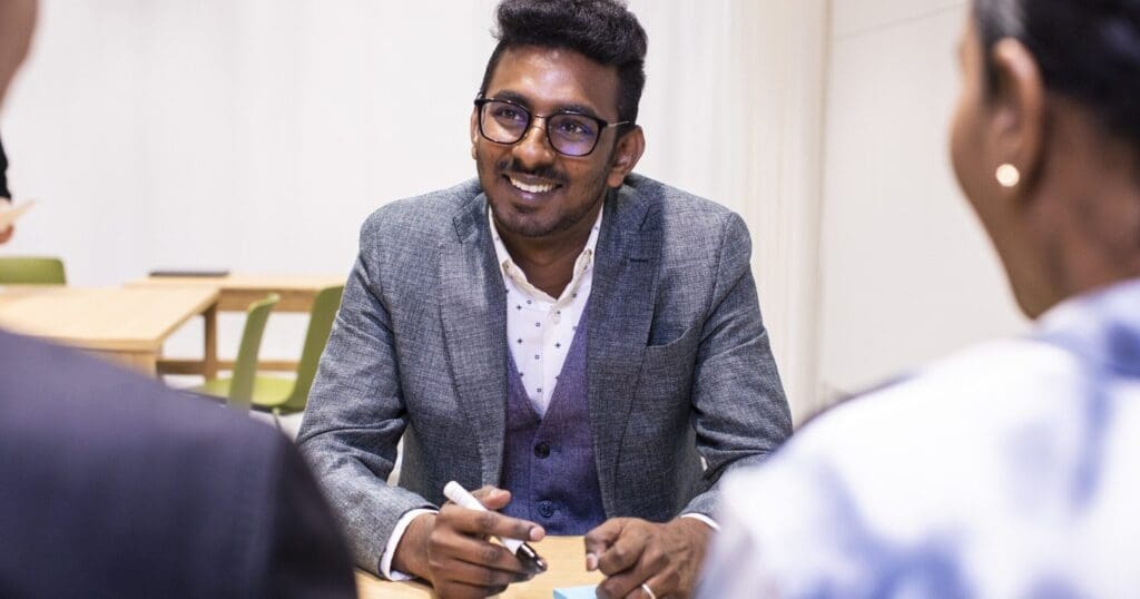 Smiling man in a meeting writing on a post-it note