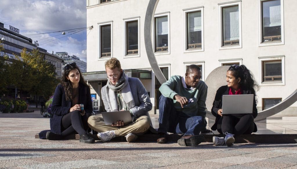 Group of people sitting outside with laptops