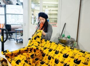 Woman inspecting a piece of yellow fabric with an elephant pattern