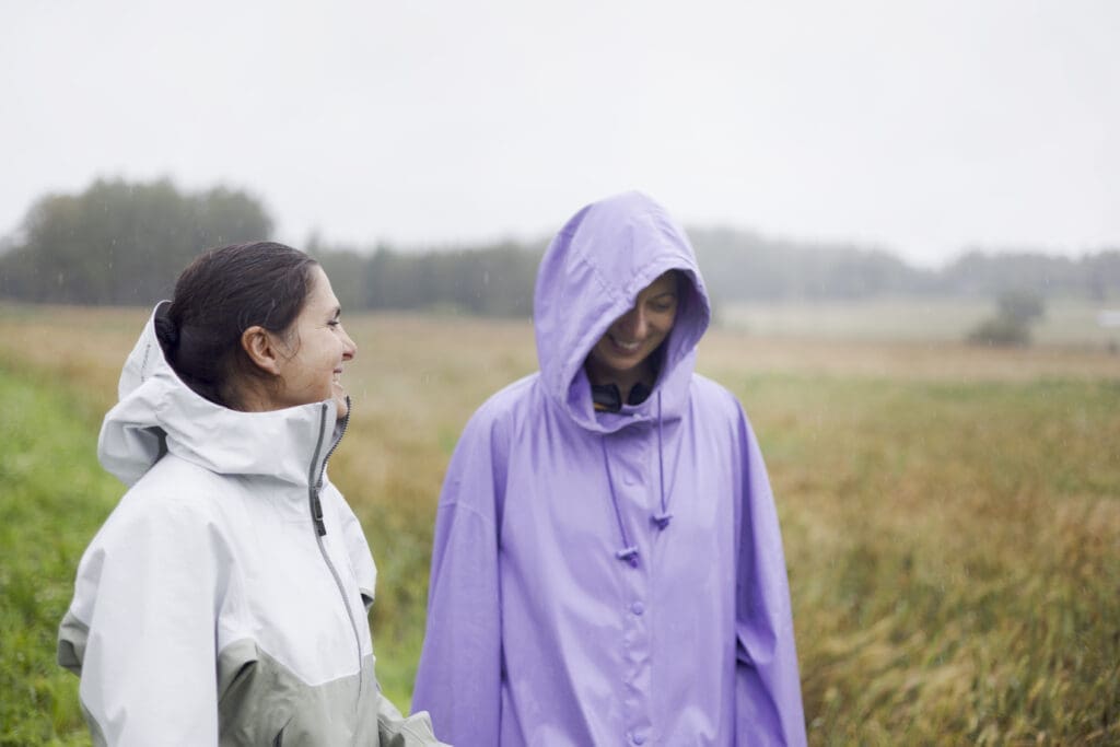 Two women laughing in a field during a summer shower