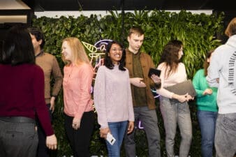 A group of people mingling happily in front of a green wall.